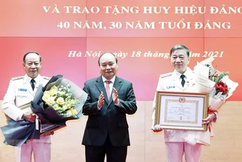 Chủ tịch nước Nguyễn Xuân Phúc trao tặng Huy hiệu 40 năm tuổi Đảng cho Đại tướng Tô Lâm, Ủy viên Bộ Chính trị, Bộ trưởng Công an, và Thượng tướng Lê Quý Vương, nguyên Ủy viên Trung ương Đảng, nguyên Thứ trưởng Công an. (Ảnh: TTXVN)