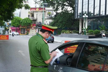 Lực lượng chức năng quận Ba Đình kiểm tra giấy đi đường của người dân tại chốt kiểm soát phòng chống dịch Covid trên đường Thanh Niên. (Ảnh: DUY LINH) 
