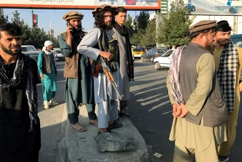 Một tay súng Taliban (giữa) đứng bên ngoài sân bay quốc tế Hamid Karzai, tại Kabul, ngày 16/8. (Ảnh: Reuters)