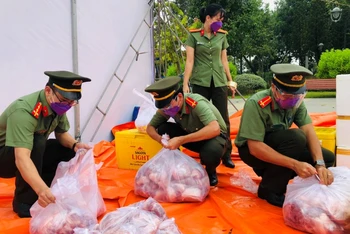 Chiến sĩ Công an tỉnh Đồng Nai chia thịt heo ra từng gói nhỏ trước khi đưa đi trao tặng người dân.