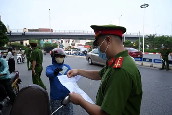Lực lượng chức năng kiểm tra giấy đi đường của người dân lưu thông trên tuyến đường Thanh Niên (Hà Nội). Ảnh: MINH HÀ