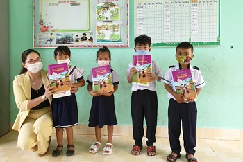 Cô Doãn Kim Huế, Hiệu trường Trường Tiểu học Cao Bá Quát trao sách giáo dục địa phương và tập vở do Báo Nhân Dân vận động cho các em học sinh. (Ảnh: Phúc Thắng)