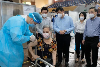 Bộ trưởng Nguyễn Thanh Long kiểm tra điểm tiêm ở nhà thi đấu Trịnh Hoài Đức, thăm hỏi những người tới tiêm. (Ảnh: Bộ Y tế)
