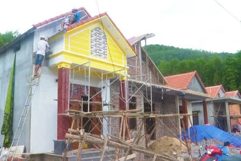 Người dân xã Thạch Hóa, huyện Tuyên Hóa hoàn thiện những công đoạn cuối để đưa nhà mới vào ở.
