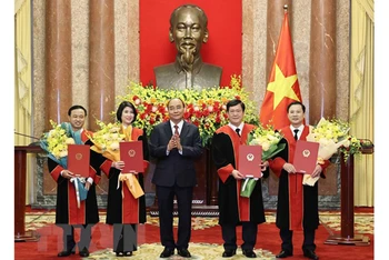 Chủ tịch nước Nguyễn Xuân Phúc trao quyết định và tặng hoa chúc mừng 4 thẩm phán Tòa án Nhân dân tối cao. (Ảnh: TTXVN) 