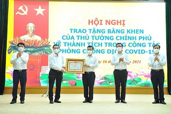 Chủ tịch UBND TP Hà Nội Chu Ngọc Anh trao Bằng khen của Thủ tướng Chính phủ cho nhân dân và cán bộ huyện Đông Anh về thành tích trong công tác phòng, chống dịch Covid-19.