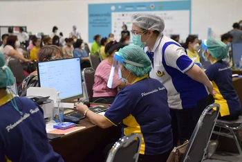 Nhân viên y tế kiểm tra thông tin của người dân tại một điểm tiêm chủng ở Bangkok. (Ảnh: NAM ĐÔNG)