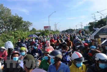 Hàng nghìn người dân chờ đợi qua chốt kiểm soát dịch trên Quốc lộ 1 (giáp ranh Long An và Tiền Giang) để về quê. (Ảnh: TTXVN)