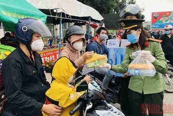 Nữ chiến sĩ Công an tỉnh Đồng Nai phát thức ăn, nước uống cho người dân về quê.