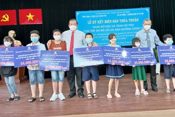 Đại diện Sở Lao động, Thương binh và Xã hội TP Hồ Chí Minh và EVNHCMC trao hỗ trợ cho học sinh mồ côi cha, mẹ trong dịch Covid-19.