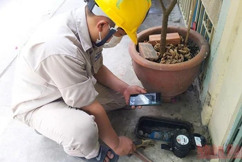 Nhân viên một Công ty cổ phần cấp nước tại TP Hồ Chí Minh kiểm tra đồng hồ nước tại nhà dân.