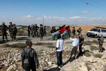 Người biểu tình cầm cờ Palestine phản đối khu định cư của Israel ở Bờ Tây. (Ảnh: Reuters)