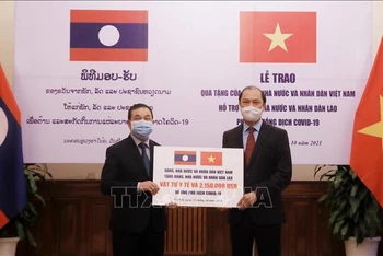 Thứ trưởng Ngoại giao Nguyễn Quốc Dũng trao tượng trưng khoản hỗ trợ của Việt Nam giúp Lào ứng phó dịch Covid-19 cho Đại sứ Lào tại Việt Nam Sengphet Houngboungnuang. Ảnh: TTXVN