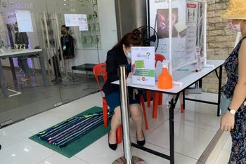 Khách hàng phải chứng minh đã tiêm đủ mũi vaccine phòng Covid-19 mới được vào sử dụng dịch vụ tại một cửa hàng ở Thủ đô Vientiane. (Ảnh: Xuân Sơn)
