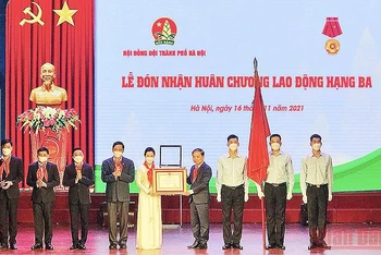 Đồng chí Phạm Tất Thắng (thứ tư từ bên phải sang trong ảnh) thừa ủy quyền của Chủ tịch nước, trao Huân chương Lao động hạng ba tặng Hội đồng Đội thành phố Hà Nội. 