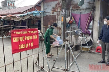Người dân nhận nhu yếu phẩm trong khu cách ly ở chợ Phụ Long, phường Trần Tế Xương, thành phố Nam Định.