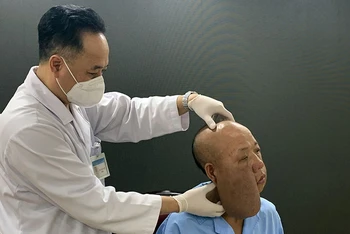 PGS, TS Trần Cao Bính, Giám đốc Bệnh viện Răng Hàm mặt Trung ương thăm khám cho bệnh nhân trước khi phẫu thuật.