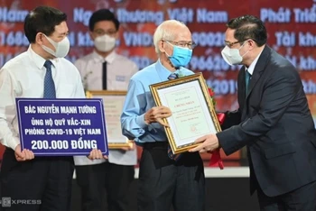 Thủ tướng Chính phủ Phạm Minh Chính trao chứng nhận, hoa cảm ơn bác Nguyễn Mạnh Tường 82 tuổi, cán bộ hưu trí ngành đường sắt đã đóng góp cho Quỹ vaccine phòng Covid-19.