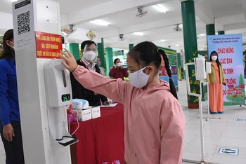 Học sinh lớp 1 Trường Tiểu học Núi Thành (Đà Nẵng) đo thân nhiệt, rửa tay sát khuẩn trước khi vào lớp.