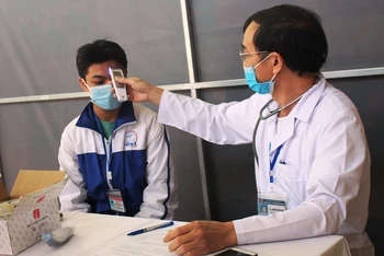 Nhân viên y tế thăm, khám sức khỏe, kiểm tra thân nhiệt học sinh trước khi tiêm.