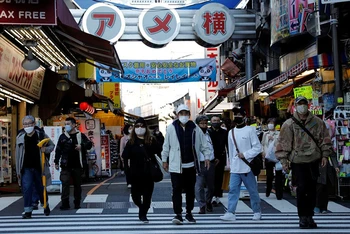 Người dân đeo khẩu trang khi đi vào phố mua sắm Ameyoko tại thủ đô Tokyo, tháng 12/2021. (Ảnh: Reuters)