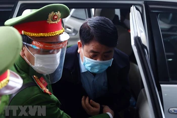 Bị cáo Nguyễn Đức Chung (cựu Chủ tịch Ủy ban Nhân dân thành phố Hà Nội) được lực lượng chức năng dẫn giải đến phiên tòa. (Ảnh: TTXVN)