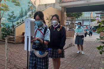 Học sinh Trường THCS Lý Phong, quận 5 đo thân nhiệt, sát khuẩn trước khi vào trường học.