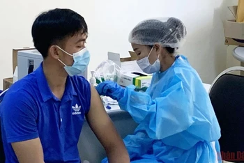 Tiêm vaccine ngừa Covid-19 mũi ba tại Bệnh viện Hữu nghị, nhằm chuẩn bị cho mở cửa quốc gia của Lào. (Ảnh: Xuân Sơn)