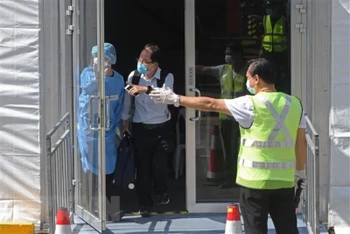 Nhân viên hướng dẫn hành khách trong chương trình Làn đi lại cho người đã tiêm vaccine (VTL), tại Singapore. (Ảnh: THX/TTXVN)