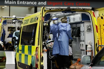 Nhân viên y tế chuyển bệnh nhân Covid-19 tới bệnh viện ở London, Anh. (Ảnh: AFP/TTXVN)