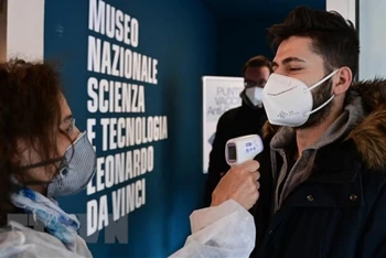 Nhân viên y tế kiểm tra thân nhiệt phòng lây nhiễm Covid-19 tại Milan, Italy. (Ảnh: AFP/TTXVN)