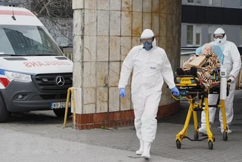 Nhân viên y tế chuyển bệnh nhân Covid-19 vào bệnh viện ở Warsaw, Ba Lan. (Ảnh: AFP/TTXVN)