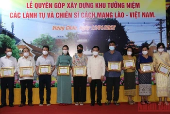 Bộ trưởng Nội vụ Lào Thongchanh Manixay (thứ năm từ phải qua trái) trao tặng Giấy khen cho kiều bào tại Lào đã ủng hộ người dân Lào, tối 12/1. (Ảnh: Xuân Sơn)