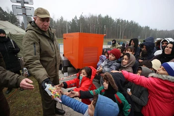 Những người di cư nhận đồ cứu trợ nhân đạo tại khu vực biên giới Belarus-Ba Lan, tháng 11/2021. (Ảnh: Reuters)