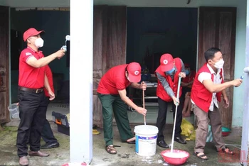 Các tình nguyện viên chữ thập đỏ sơn nhà cho các hộ gia đình khó khăn.