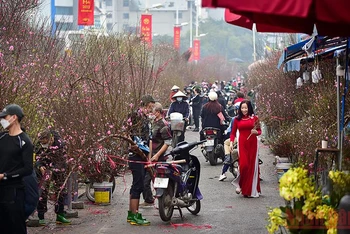 Đâu đó là hình ảnh thiếu nữ với tà áo dài đỏ đi giữa cảnh tập nập ở chợ hoa Quảng Bá. (Ảnh: Thành Đạt)