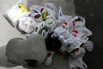 Một phụ nữ Singapore dùng nhiều túi ni-lông để dự trữ thực phẩm sau khi Singapore nâng mức cảnh báo dịch Covid-19 lên da cam ngày 8/2/2020. Ảnh: Reuters.