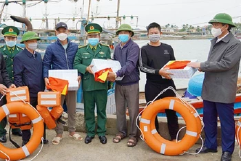 Chủ tịch tỉnh Quảng Bình Trần Thắng (bên phải) tặng quà và cờ Tổ quốc cho ngư dân.