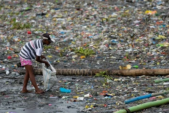 Một người phụ nữ nhặt những chiếc cốc nhựa bị vứt ra ngoài môi trường dọc bờ sông Pasig ở Manila, Philippines, ngày 10/6/2021. (Ảnh: Reuters)