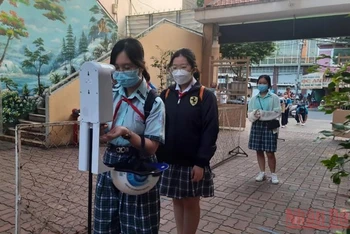 Học sinh Trường THCS Lý Phong, quận 5, TP Hồ Chí Minh kiểm tra thân nhiệt, sát khuẩn trước khi vào lớp học.