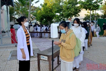 Học sinh thực hiện kiểm tra thân nhiệt và rửa tay sát khuẩn trước khi vào lớp học tại Trường trung học phổ thông Phan Bội Châu, thành phố Phan Thiết (Bình Thuận).
