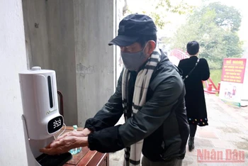 Du khách sát khuẩn tay và đo thân nhiệt trước khi vào tham quan di tích Đền Ngọc Sơn, quận Hoàn Kiếm, Hà Nội. (Ảnh: DUY LINH)