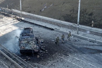 Binh sĩ Ukraine di chuyển qua 1 chiếc xe bị hư hỏng tại khu vực giao tranh với quân đội Nga ở thủ đô Kiev, Ukraine, ngày 26/2/2022. (Ảnh: Reuters)