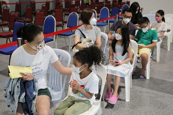 Cha mẹ đi cùng trẻ 5-11 tuổi khi tiêm phòng vaccine ngừa Covid-19 tại Kuala Lumpur, Malaysia. Ảnh: Reuters