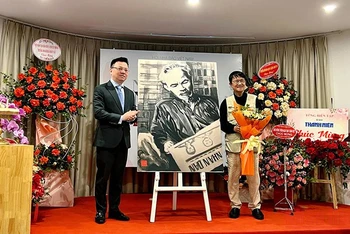 Đồng chí Lê Quốc Minh thay mặt Hội Nhà báo Việt Nam nhận bức vẽ “Bác Hồ đọc Báo Nhân Dân” do tác giả Huỳnh Dũng Nhân trao tặng.