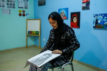 Roya Rasuli giới thiệu một trong những bức vẽ của cô tại trại tị nạn Thiva, Hy Lạp, ngày 3/3/2022. (Ảnh: REUTERS)