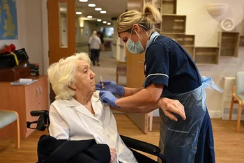 Nhân viên y tế tiêm vaccine phòng COVID-19 cho một cụ bà ở Wigan (Anh). (Ảnh: AFP/TTXVN)