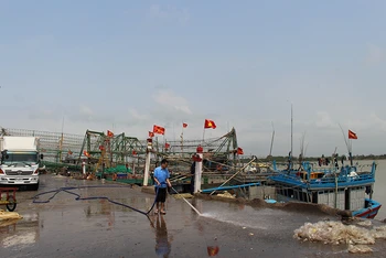 Người lao động làm vệ sinh khu vực tàu cá cập Cảng Hới bốc, dỡ hải sản.