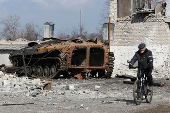 Người dân đạp xe qua một khu vực tại vùng Donetsk, Ukraine, ngày 15/3. (Ảnh: Reuters)