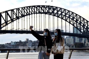 Du khách chụp ảnh tại khu vực Cầu Cảng Sydney, Australia. (Ảnh: AFP/TTXVN)